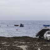 ...mentre un signore sta tirando su dall�acqua con il carrello un gommone grigio